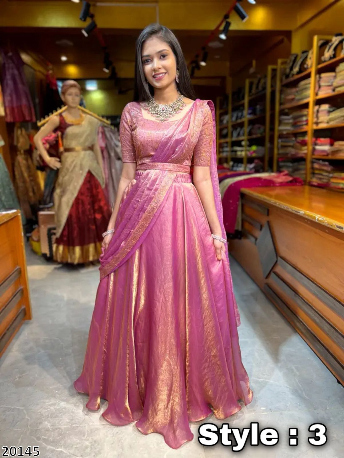 Woman in a pink saree standing in a store with mannequins in the background